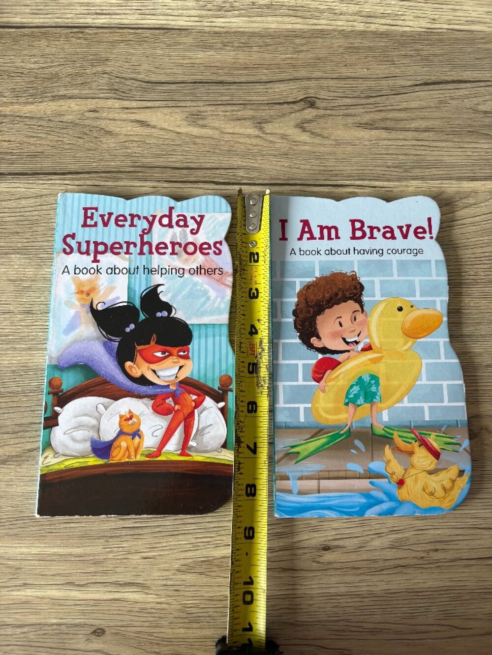 Two children's shaped board books titled Everyday Superheroes and I Am Brave!